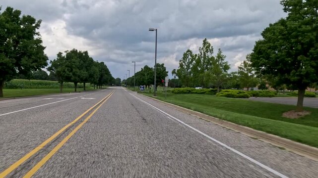 Moving vehicle perspective entering a modern Midwest university campus past contemporary brick buildings and directional signs. Captured at University of Illinois Springfield.