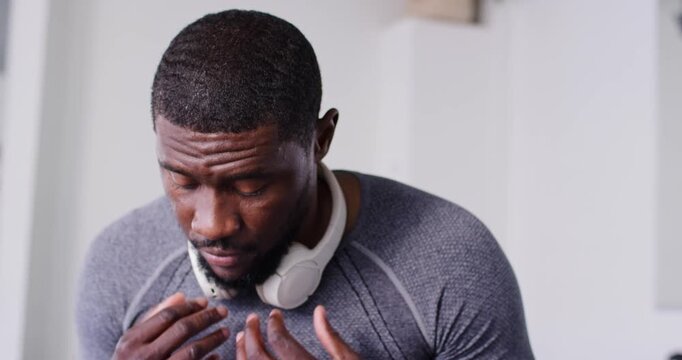 Man lifting white headphones onto head after brief pause, adjusting fit, settling to listen at home