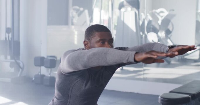 African American man shifting weight, lowering squats at gym bench, wearing top and watch for power