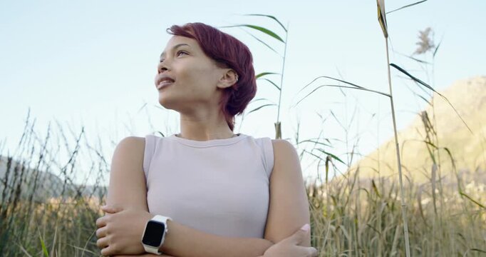 African American woman 20s standing in reeds by mountain in tank in sun, gazing, smiling, tilting