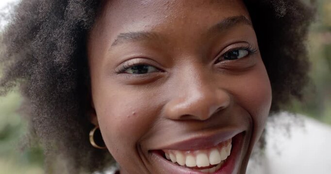 Female facing camera, reacting with smile growing into laugh on porch cushion showing earring