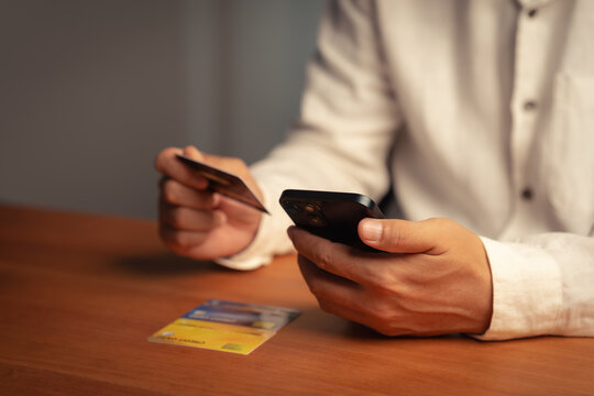 Adult man uses a smartphone and credit card for online shopping and payment. This e-commerce technology allows secure mobile banking, finance, and business transactions over the internet.