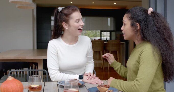 Diverse female friends sitting table near door holding hands, green talking, sharing, reaching tart