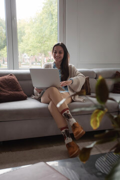 Happy young woman smiling at laptop screen during video call at home