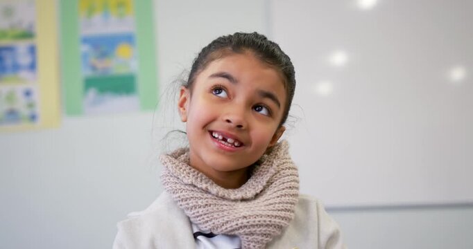 African American girl child smiling and reacting to off-camera question in classroom wearing scarf