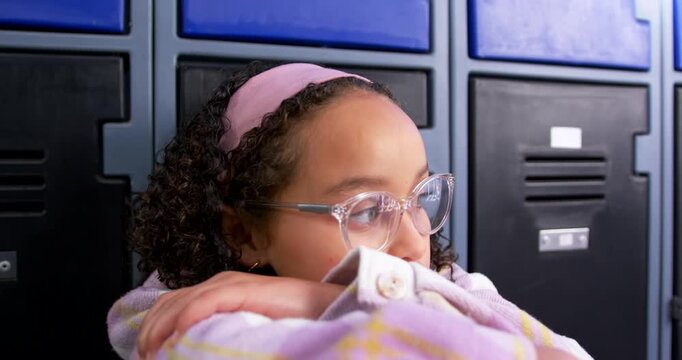 African American teen spotting motion leaning on arms turning head waiting at lockers with glasses