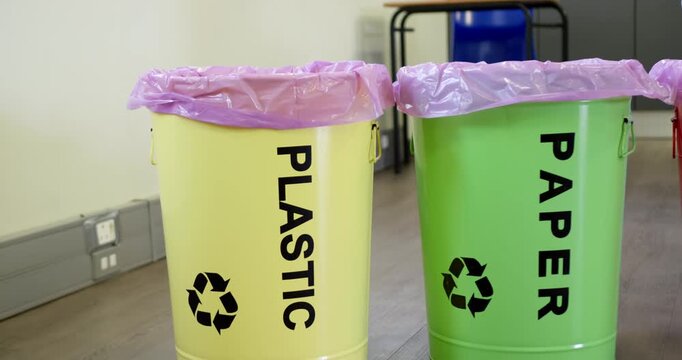 African American youth approaching PLASTIC bin in office, holding clear bottle, dropping to recycle