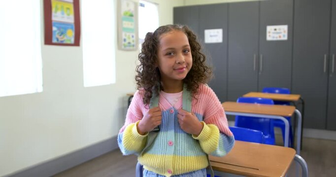 African American child holding green straps, turning to camera while sun drawing smile in classroom