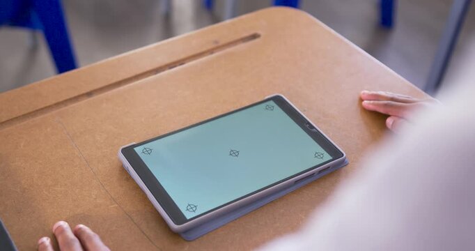 Teenage male placing hands near tablet on wooden student desk, steadying device for calibration