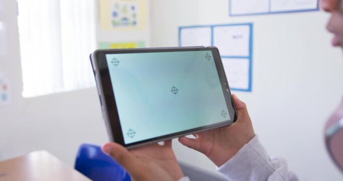 African teenage male calibrating tablet when markers show, showing blue screen with marker in class