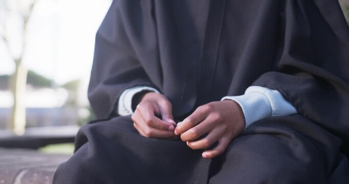 African American teen fidgeting gown, reflecting, camera pulling back revealing cap tassel on bench