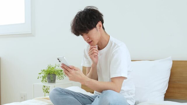 悩みながらスマートフォンを使う若い男性
