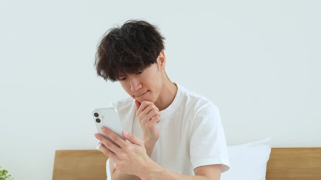 悩みながらスマートフォンを使う若い男性
