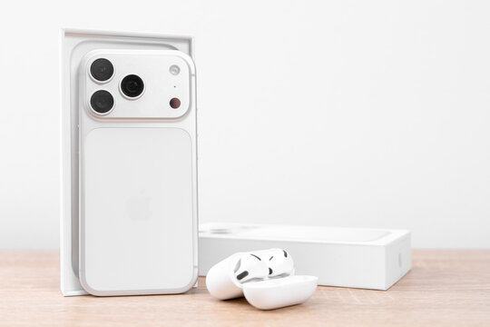 Bar, Montenegro: February 6, 2026: White apple iphone 17 pro in open box with wireless earbuds and charging case on light wooden table, new device unboxing delivery concept