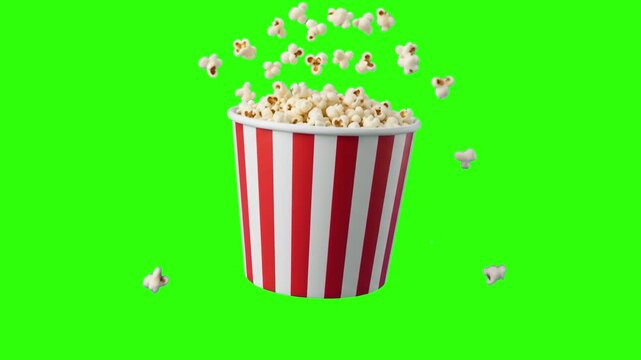 A classic red and white striped bucket filled with fresh popcorn with kernels flying in the air isolated on a green chroma key background. Ideal for cinema promos, movie night ads, and snack packaging