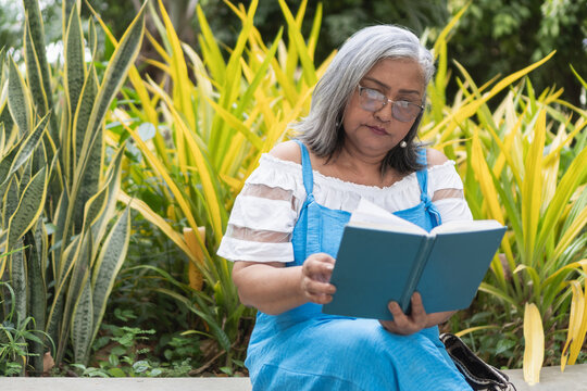 Senior woman reading book enjoying quiet garden relaxation