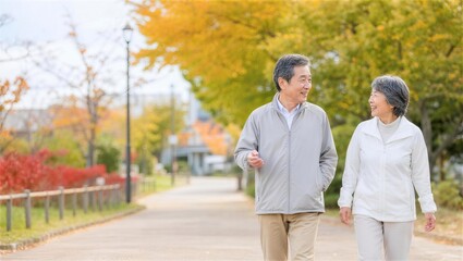 Obraz premium 紅葉した公園を会話しながら歩く日本人シニア夫婦