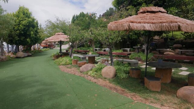 A walking camera move passes outdoor benches and shaded rest areas surrounded by landscaped greenery.