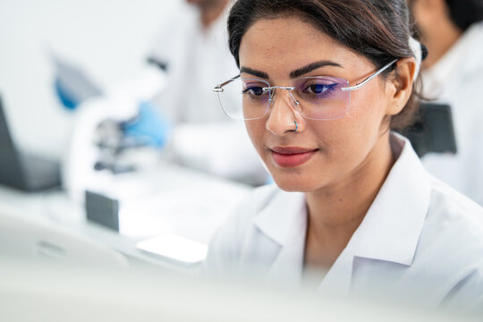 Female scientist wearing glasses looking at computer monitor display during scientific research in laboratory