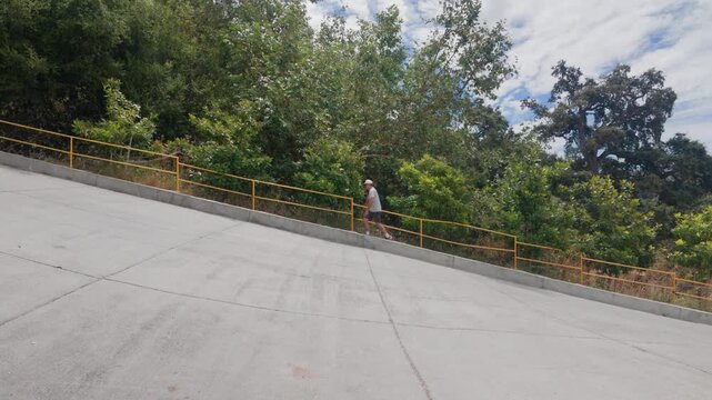 A young man walks along outdoor stairs through the dry hillside grounds of the mountain attraction.