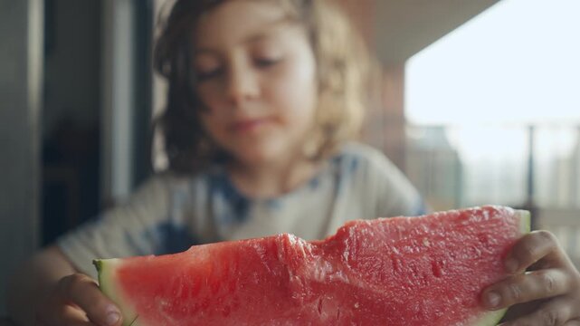 Curly-haired child looking at a large watermelon slice up close