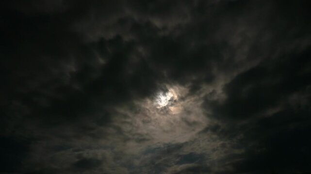 Timelapse of a full moon moving across the night sky with dark clouds passing by, creating a mysterious, spooky, and dramatic atmosphere with bright moonlight