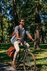 Naklejka premium Energetic Young Man Cycling Through Sunlit Urban Streets, Radiating Joy and Freedom on a Warm Summer Day