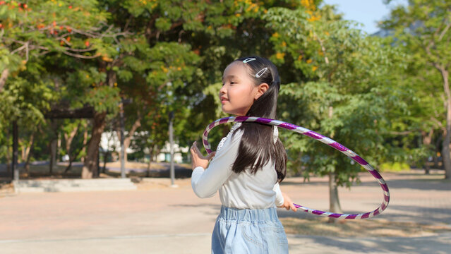 Young Thai Girl Playing with Purple Hula Hoop in Sunny Park