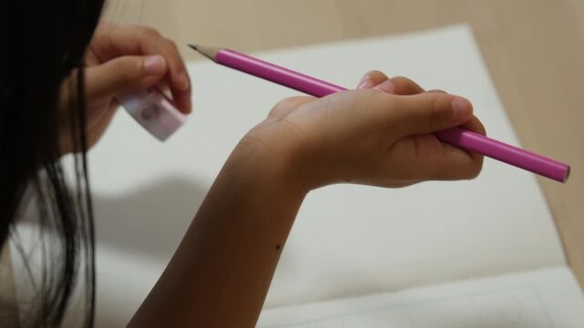 Close up of child hands sharpening a pencil with a small pencil sharpener