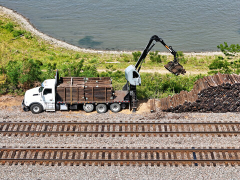 Truck-Mounted Crane moving used Railroad Ties to a truck for removal
