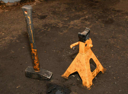 Heavy-duty hammer and orange-painted, metal ratcheting jack stand has a maximum capacity from 2 to 3 tons. These stands are designed for heavy-duty automotive use in workshops or garages.