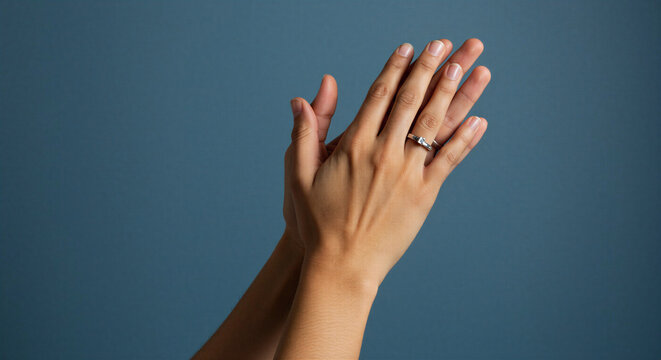 Woman's hands clapping together with ring on dark blue background  