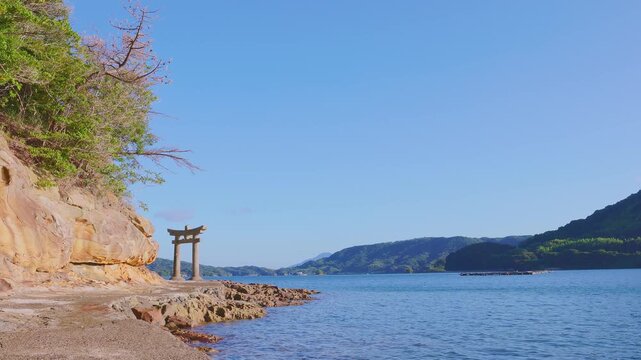 砂岩の断崖と海辺の石鳥居が織りなす穏やかな海辺の遠景（和田津美神社）