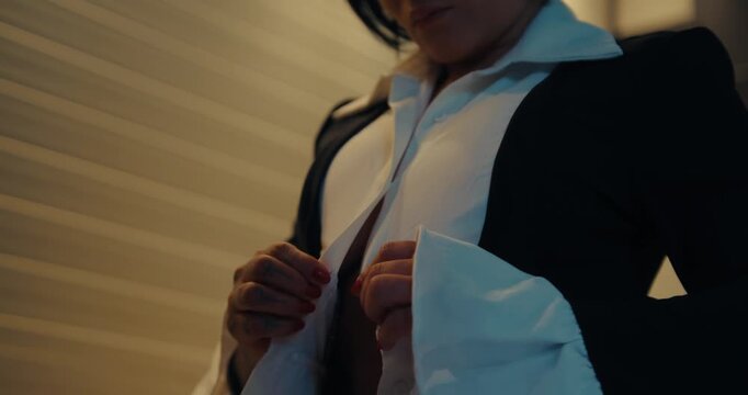 Close-Up of a Woman Buttoning a White Shirt Under a Black Blazer