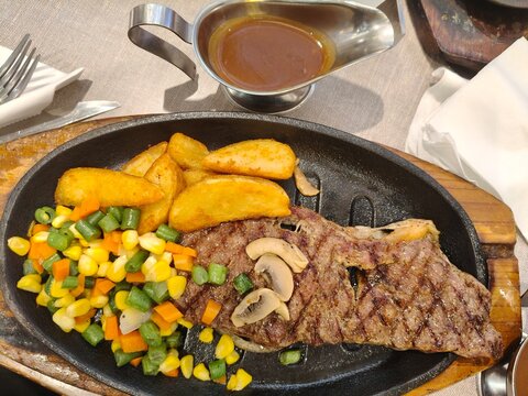 Grilled Beef Steak with Potato Wedges and Mixed Vegetables on Hot Plate