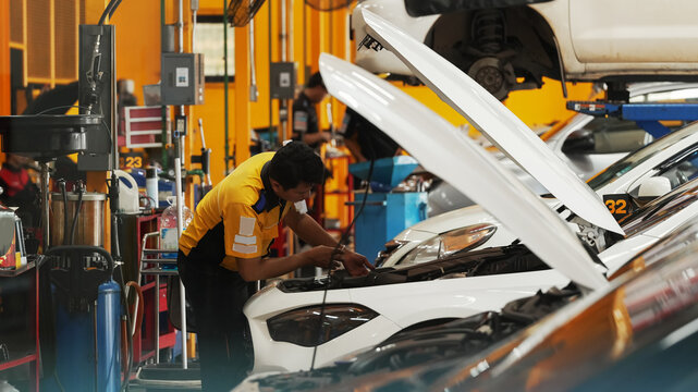 Professional auto mechanic inspecting engine during vehicle maintenance in automotive service center