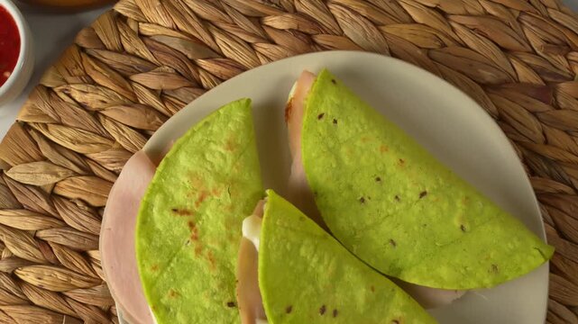 Top view of green cactus quesadillas on a round woven mat