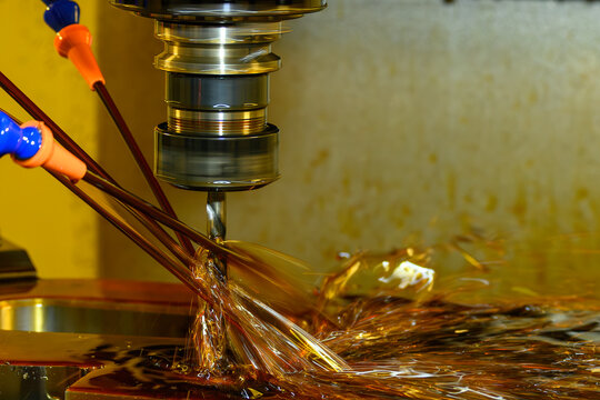 CNC milling machine performing hole drilling process using canned cycle with oil coolant fluid