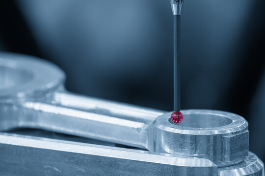 Ruby tip touch probe measuring automotive part precision in blue tone lighting