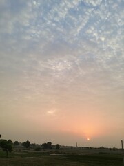 Obraz premium Beautiful Rural Sunset Over Agricultural Fields in Indian Village with Cloudy Sky