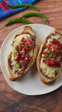 Overhead view of colorful and textured Mexican molletes on a simple white plate