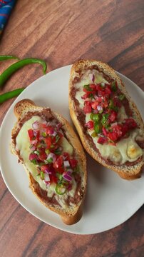 Overhead view of Mexican molletes with beans cheese and pico de gallo on white plate