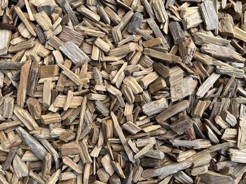 Natural brown wood chips mulch for garden landscaping. Close up of organic cedar wood chippings playground ground cover. Raw decorative bark mulch pieces flat lay surface pattern.