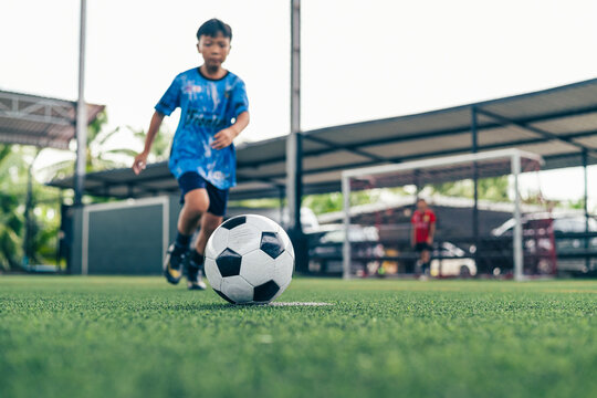 Boy kicking soccer ball conceptual metaphor for business goal success and physical health.