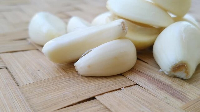 Fresh organic peeled garlic cloves spread evenly on a minimalist white surface