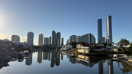 Modern City Skyline and Luxury Waterfront Homes Reflecting in Calm Canal © blueringmedia
