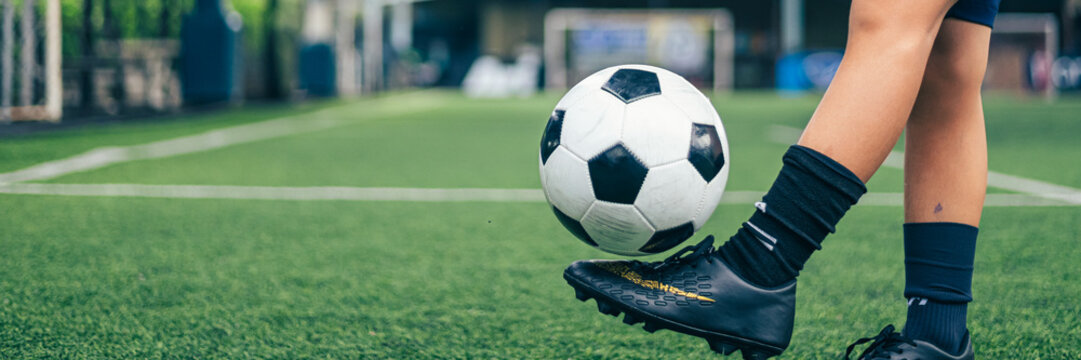 Young boy juggling soccer ball with foot at indoor field.