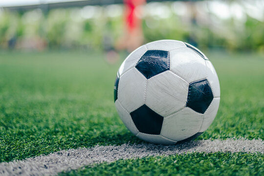 Soccer ball on white line of green turf field.