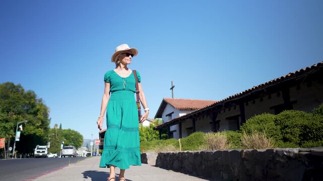 A senior woman enjoys a walk near the Mission church San Francisco Solano de Sonoma with a smile on her face in Sonoma California
