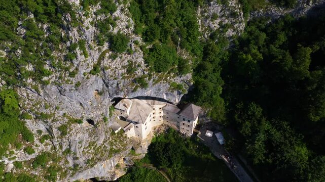 Aerial View Of Predjama Castle Reveals The Medieval Fortress Built Into The Cliffs Of The Inner Carniola Region In Slovenia.